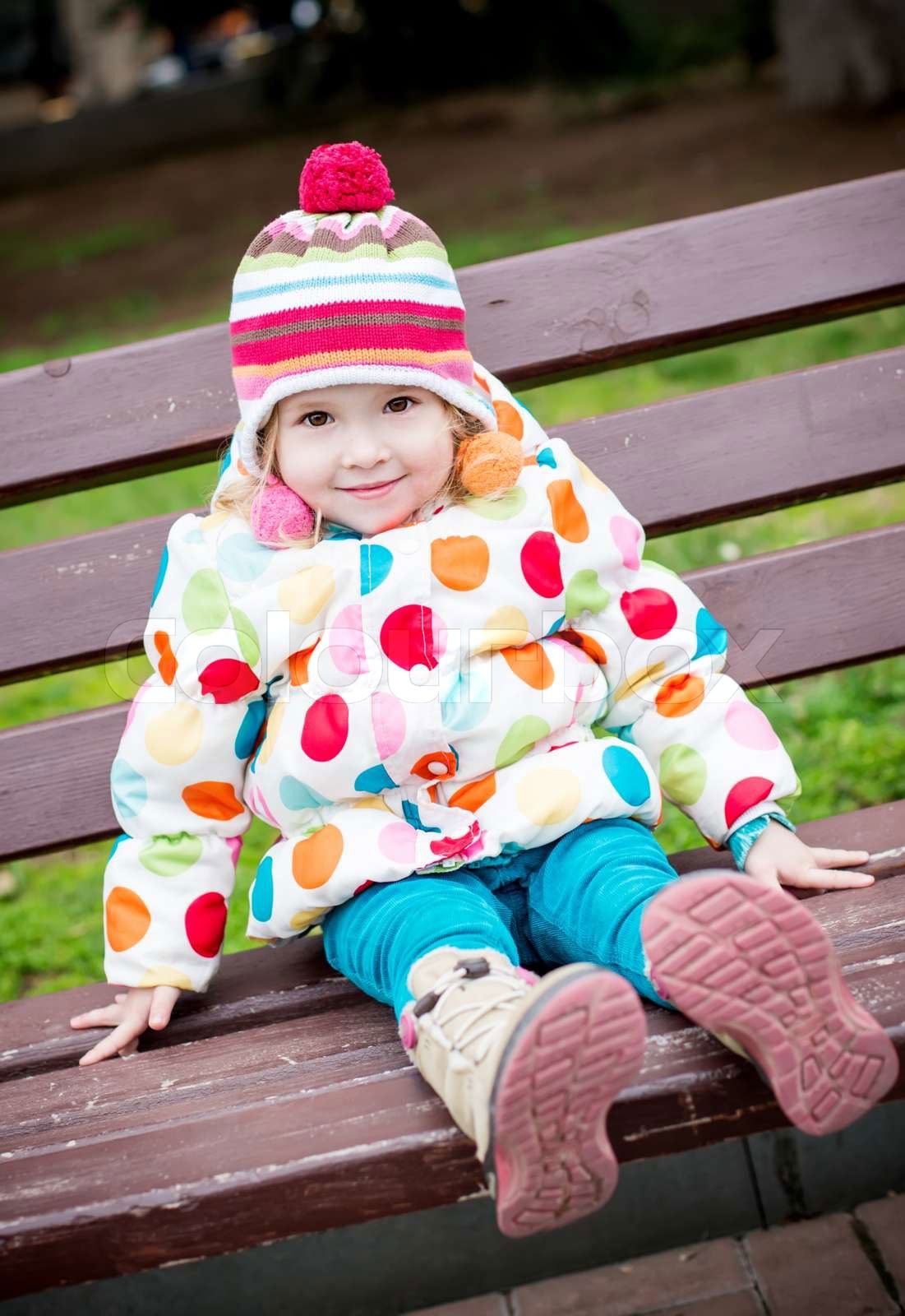 cute toddler girl sitting on the bench outdoor | Colourbox