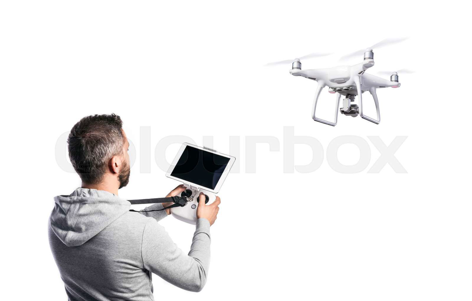 Man with remote control and flying drone with camera. Studio Colourbox