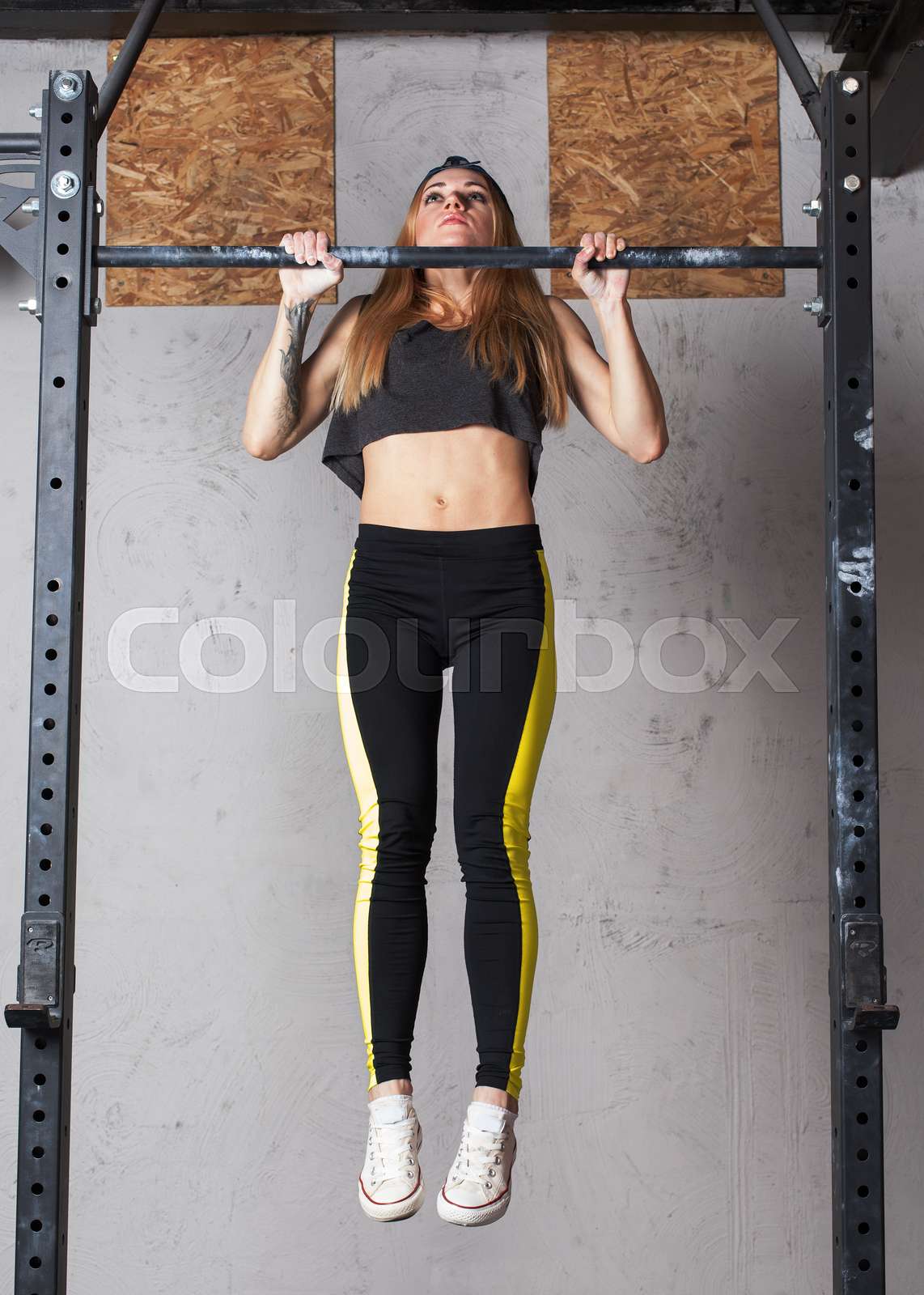 Woman athlete doing pull ups on horizontal bar in the gym Colourbox