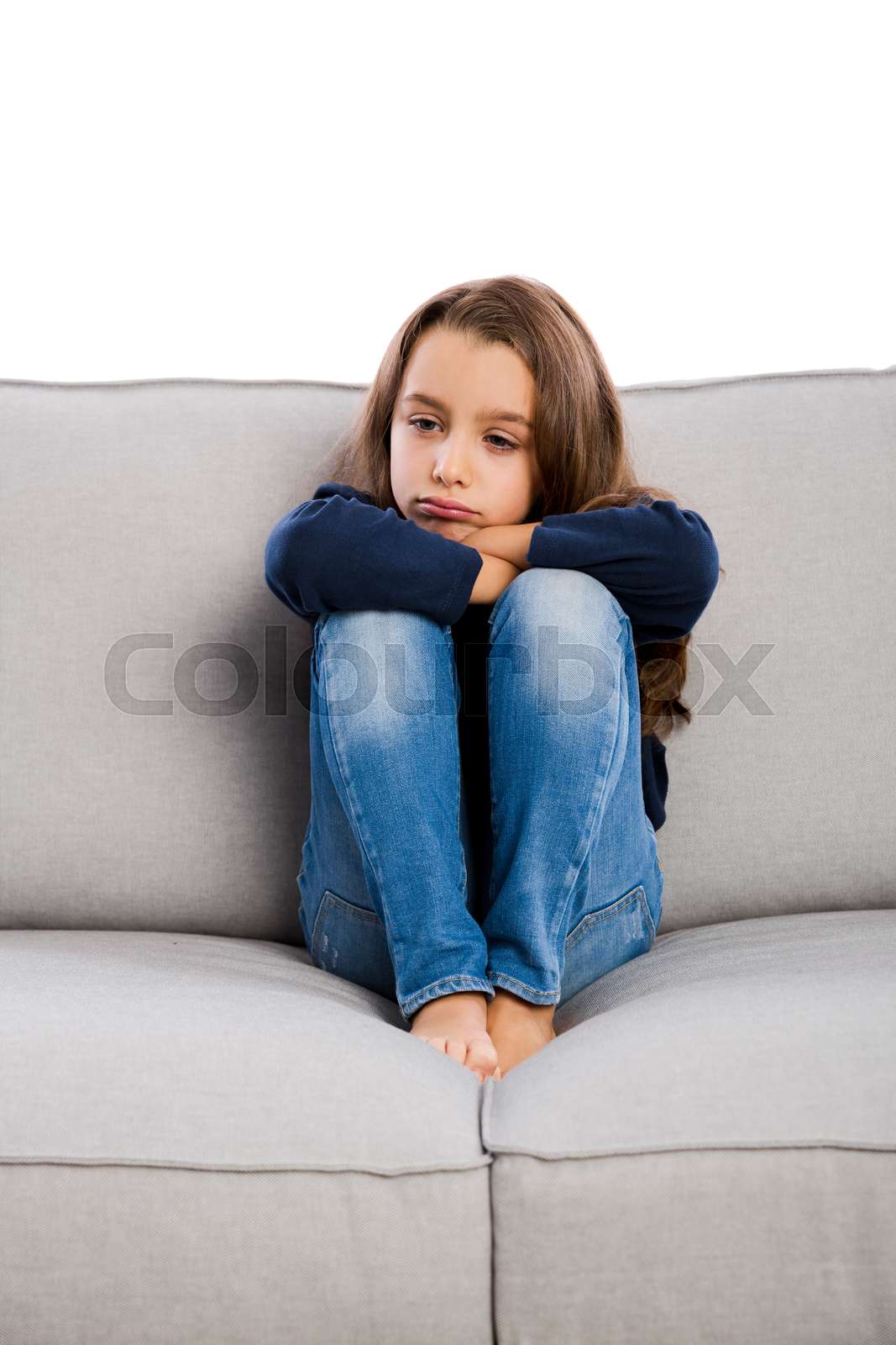 Little girl sitting on a couch and upset with something Colourbox