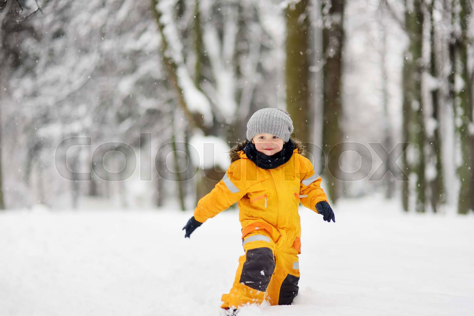 Cute little boy in yellow winter clothes walks in during a s Colourbox