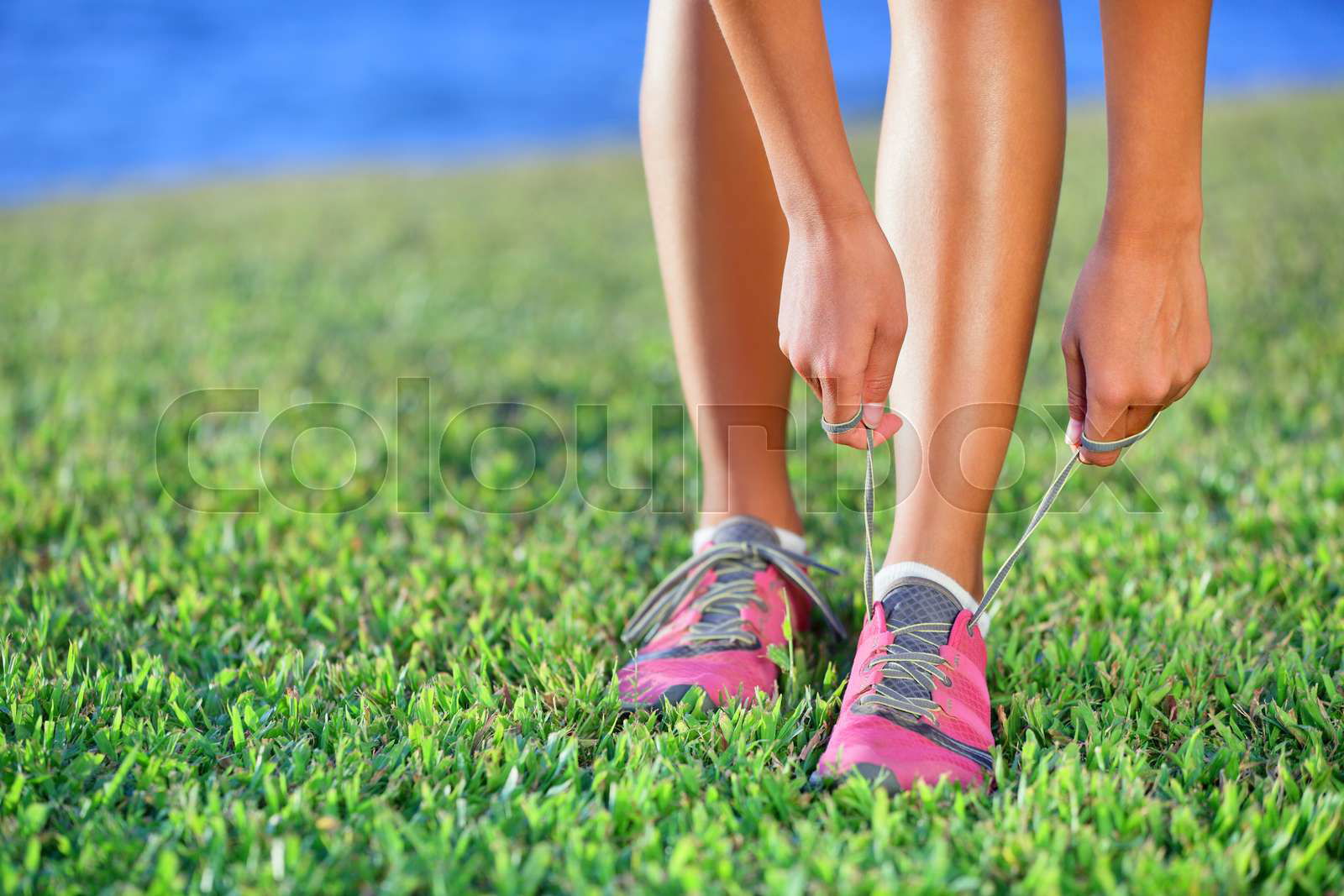 Running shoes girl on grass in summer park. Colourbox