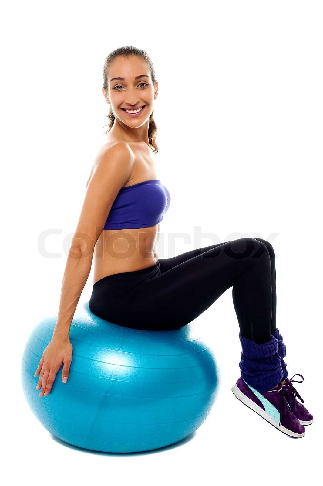 Pretty lady sitting on big blue exercise ball Stock image