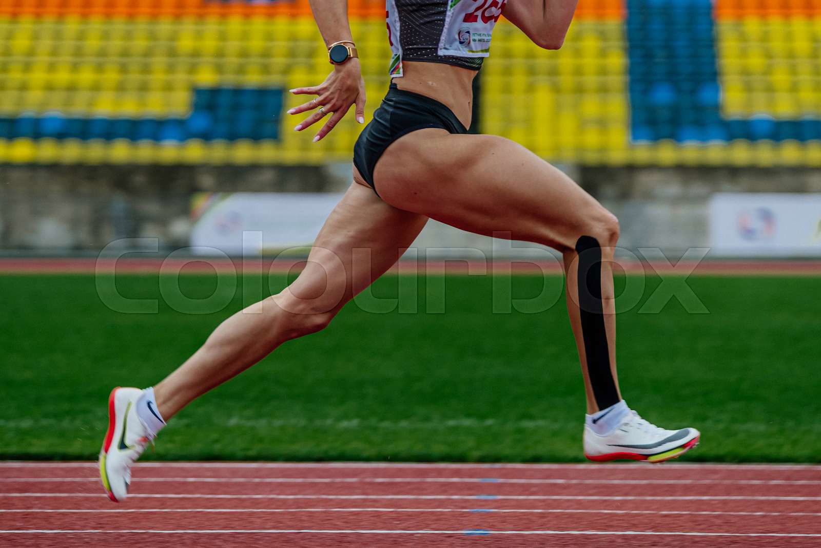 Female runner sprinter running track stadium in Nike spikes Colourbox