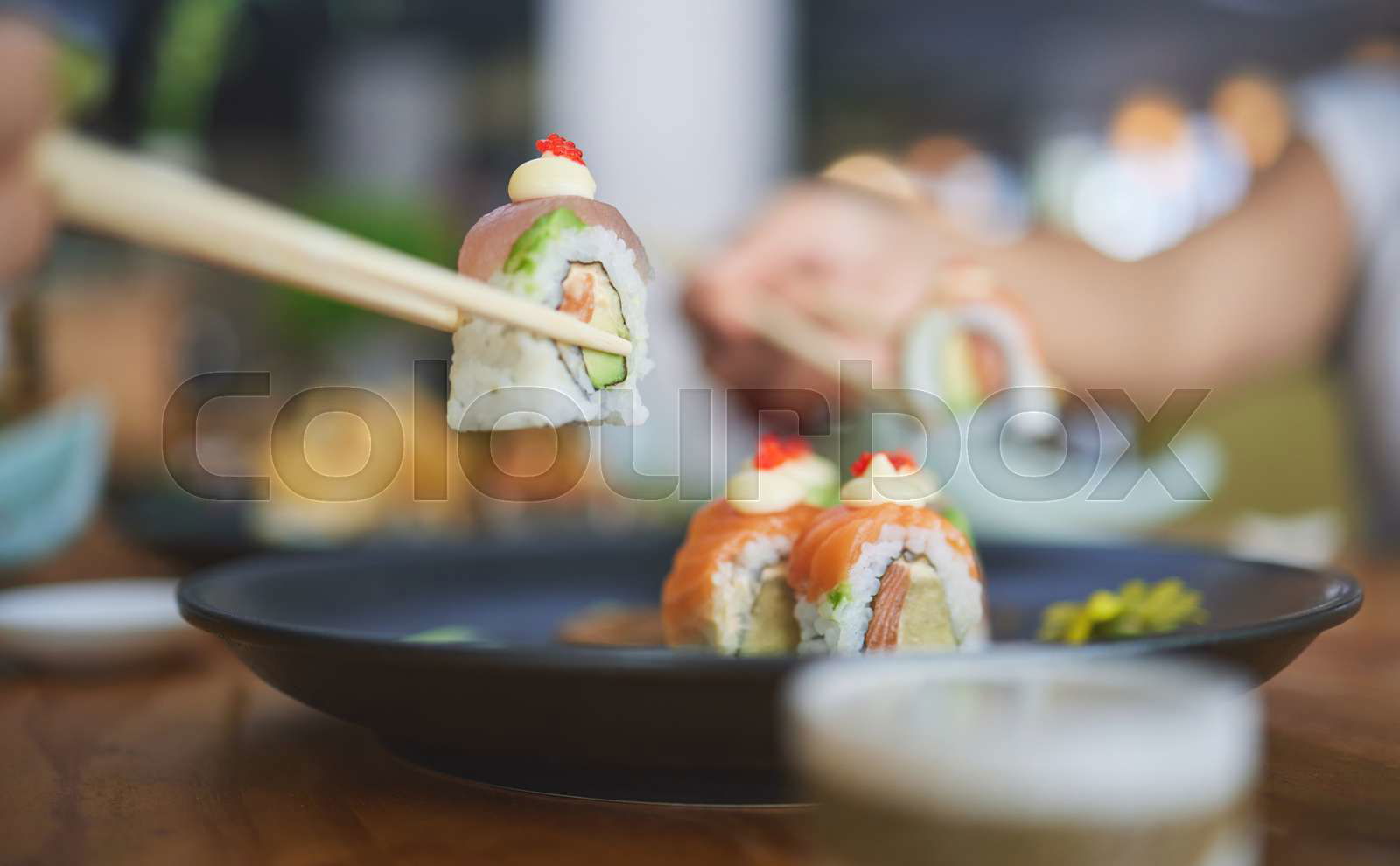 Chopstick hand and eating sushi food at restaurant for nutr Colourbox