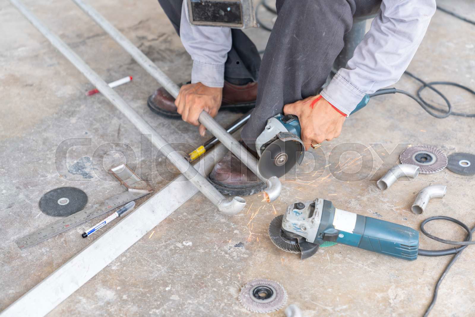Worker use electric grinding cut stainless steel pipes using Colourbox