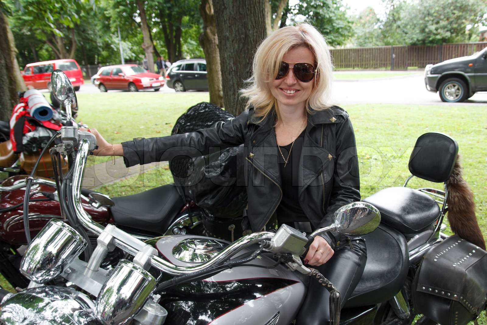 Smiling biker girl dressed in leather clothes on a motorcycl Colourbox