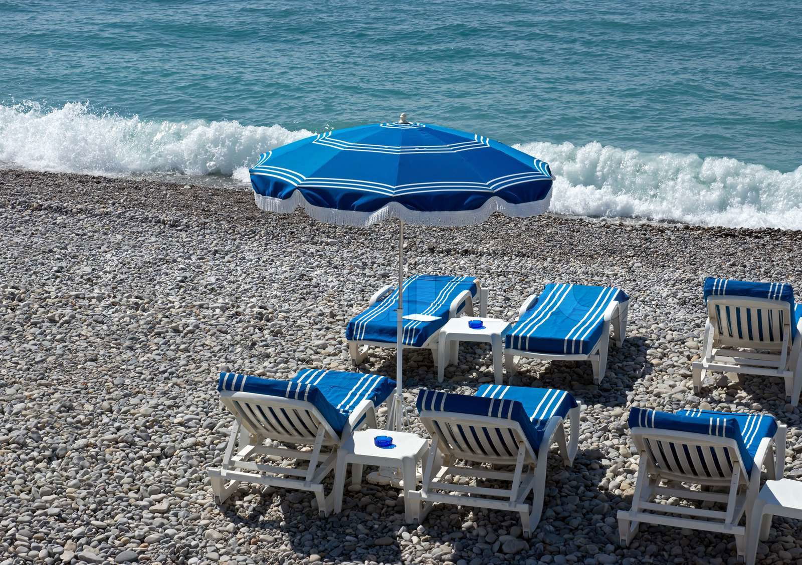 Beach with blue umbrellas near Promenade des Anglais in city Colourbox